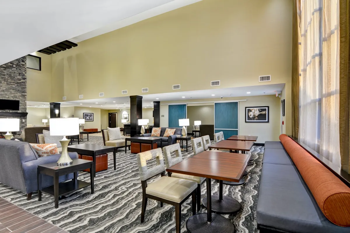 A communal interior space with cozy sofas, tables, lamps, and thoughtful artwork on the walls. The arrangement encourages conversation and relaxation, hinting at a shared lounge or multipurpose area for both work and socializing.