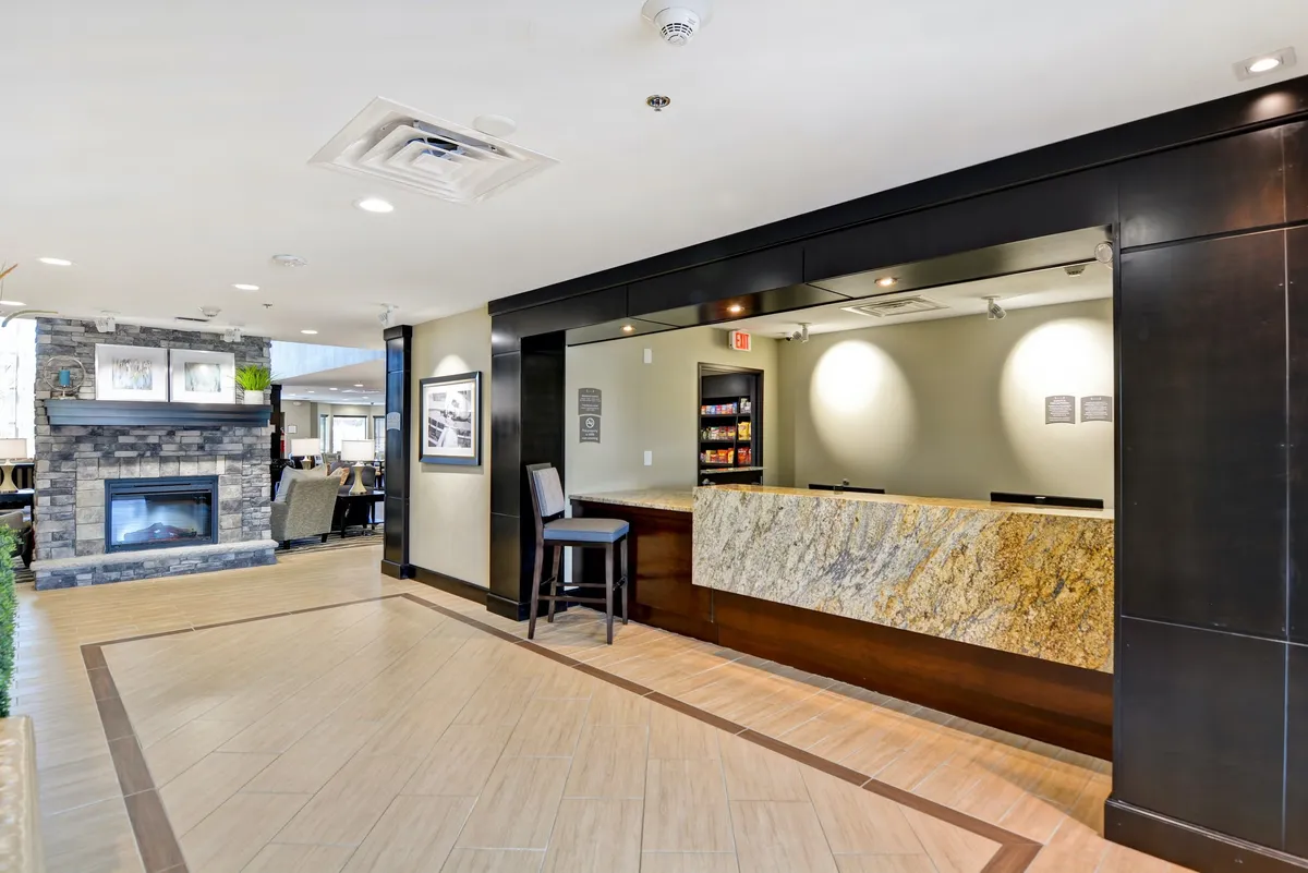 The hotel’s reception area features a welcoming front desk, a cozy fireplace, and a comfortable seating area. The ambient lighting and inviting décor set a warm, professional tone for arriving business travelers.