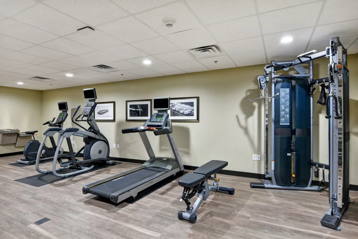 A well-equipped fitness center with treadmills, elliptical machines, a weight bench, and a strength training machine. The space is bright and motivational, ideal for maintaining workout routines during your stay.