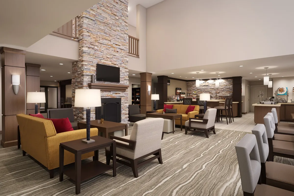 This image displays a welcoming interior featuring a comfortable seating area, modern lighting, and an open kitchen in the background. The open kitchen area is visible, providing a sense of the self-catering facilities available to guests.