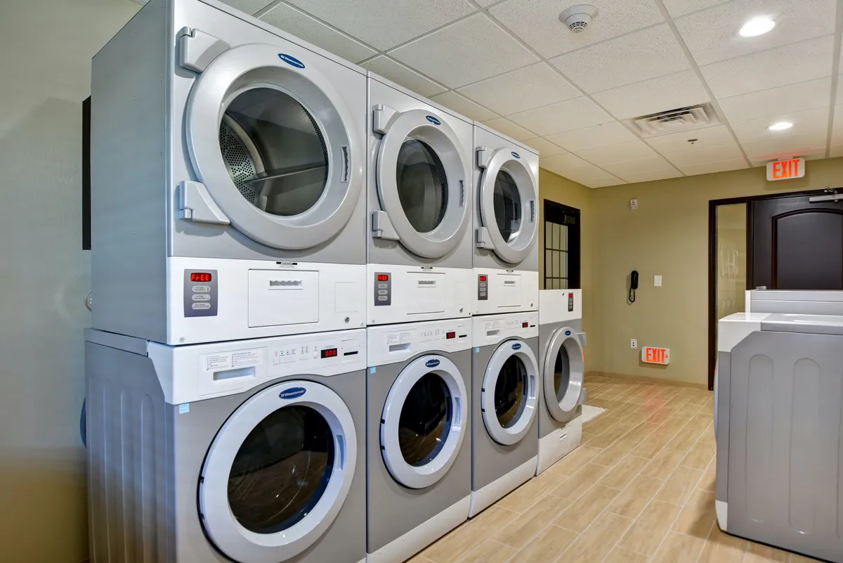 A practical laundry area with stacked washing machines, dryers, and a folding space. The setting is clean and efficient, highlighting the convenience of on-site laundry for longer stays.